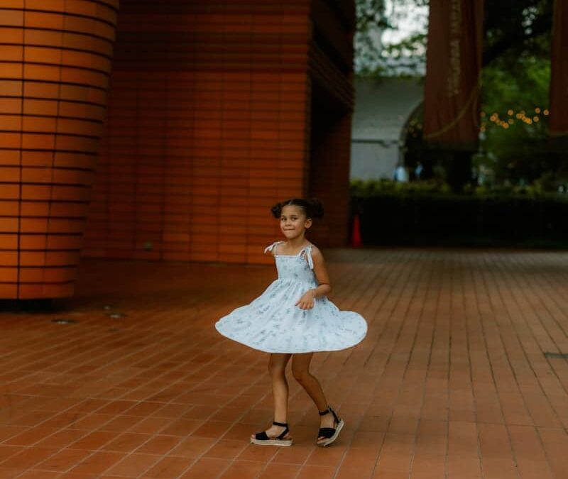 A young girl spins in a whimsical dress.